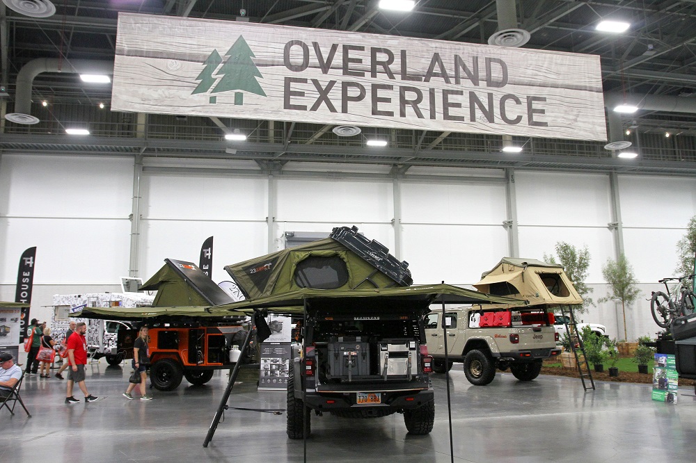 Three vehicles with roof top tents under sign for Overland Experience at SEMA Show 2022 in Las Vegas.